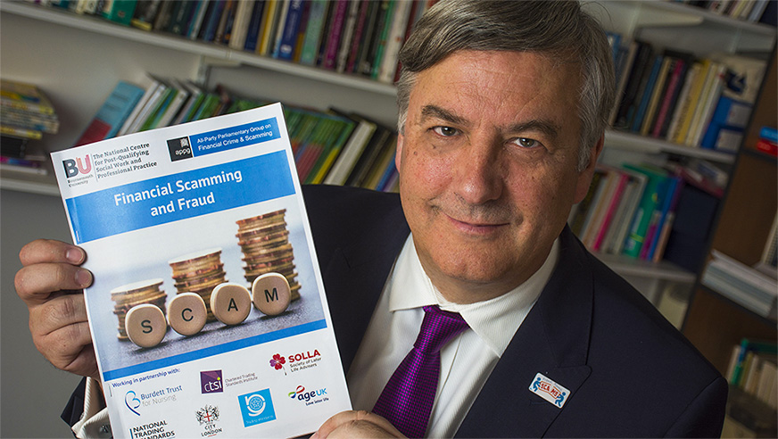 Professor Keith Brown holding the 'Financial Scamming and Fraud booklet' – one of the outputs of the research project