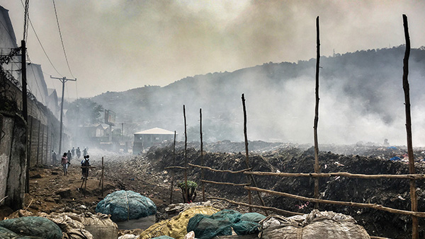 Rubbish in a landfill site in Freetown, Sierra Leone with smoke rising