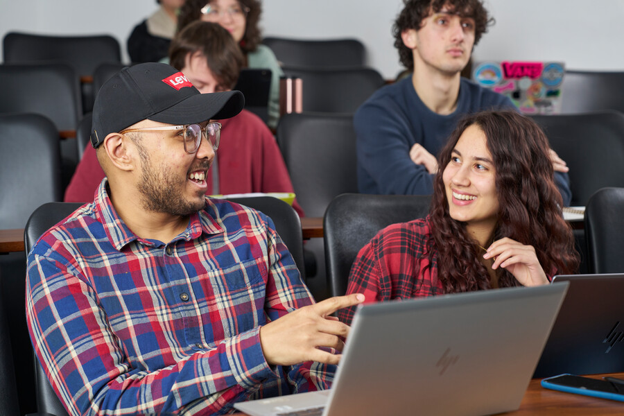 Two students discussing lecture content in a lecture theatre