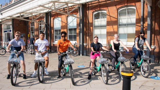 Image of students on Beryl Bikes outside of Bournemouth Train Station