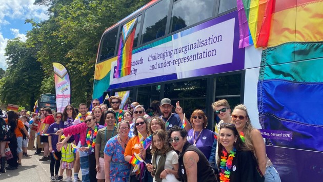 BU students and staff standing in front of a BU bus with 'Challenging marginalisation and under-representation' written on the side at Bourne Free 2024