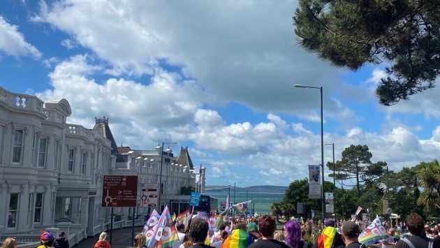 Parade goers at Bournemouth's annual Pride event walking down a hill in Bournemouth with the sea in view