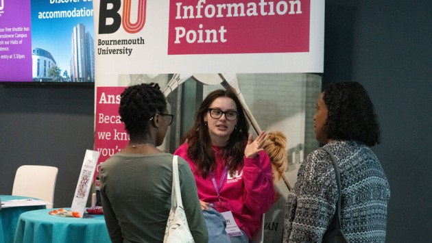Student Ambassador speaking to 2 guests at the Info Point during an Open Day