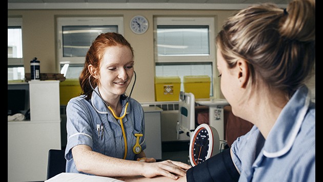 A nurse taking another the blood pressure of another nurse