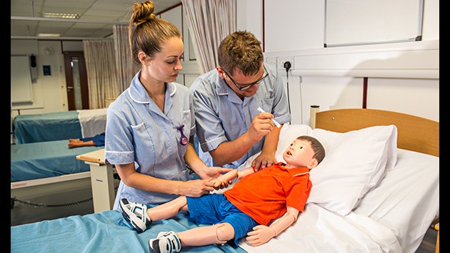 Two nursing students examining a child mannequin on the ward