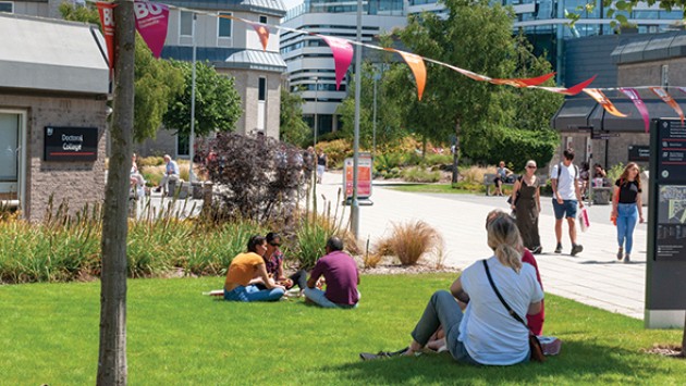 People sitting on grass outside Christchurch House on Talbot Campus on a sunny Open Day