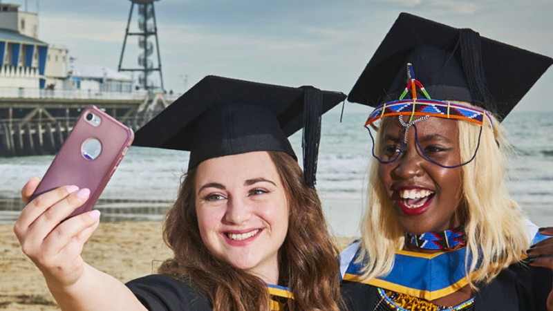 Graduates taking a selfie by the pier