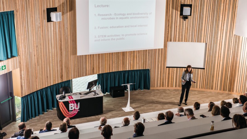 A lecture in the Fusion Building, taken from the perspective of an attendee, looking down towards the lecturer