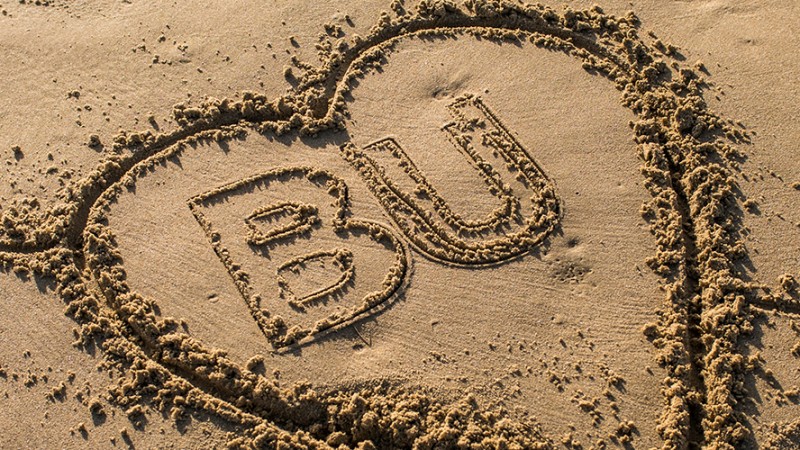 BU logo in a heart carved into beach