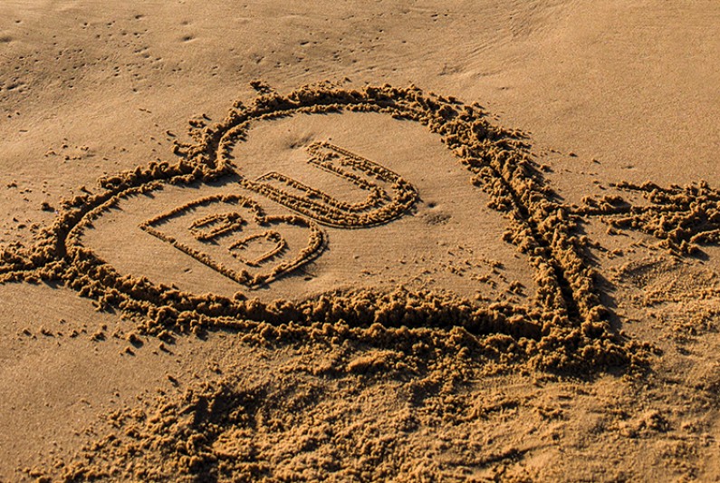 A love heart containing the BU logo carved into the sand on Bournemouth beach