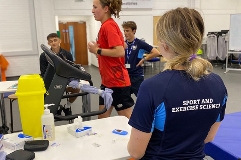An AFCB Women's Team player running on a treadmill will Bournemouth University students and staff monitoring