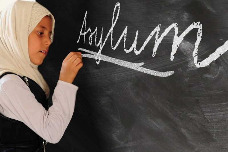 A child writing asylum on a blackboard