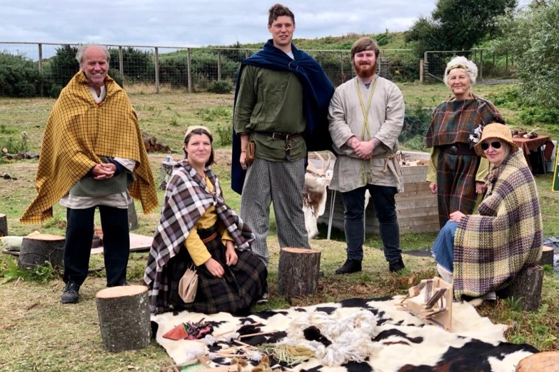 A group of actors showing textiles, tools and archaeology at Hengistbury Head