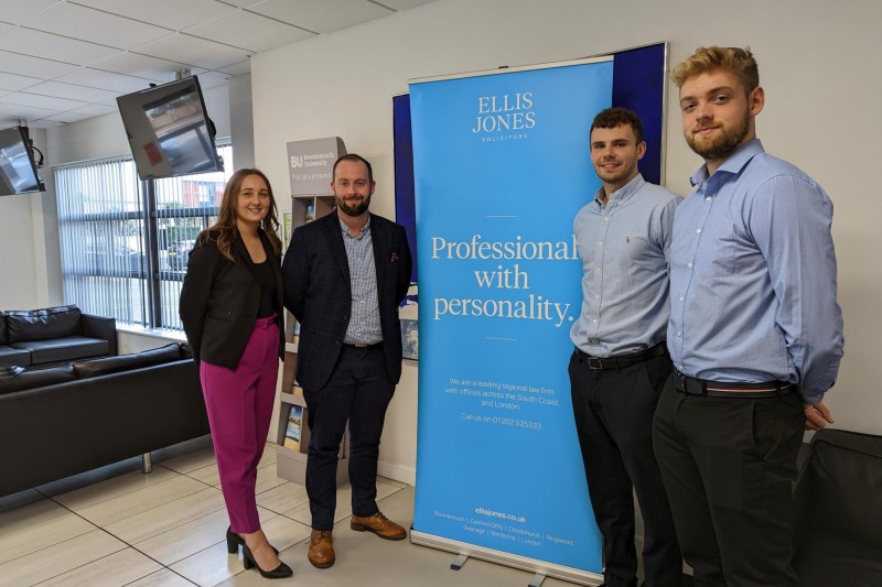 Two Men and Two Women stand either side of an Ellis jones Solicitors Banner at the Legal Skills conference