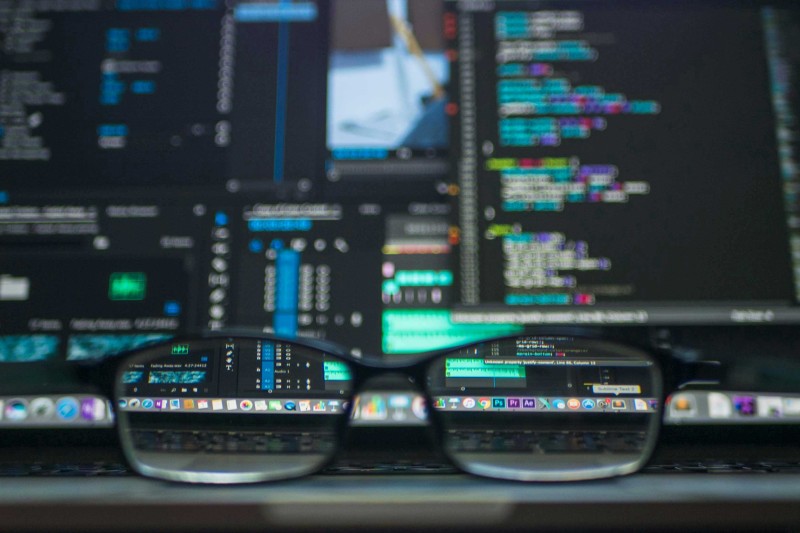 A pair of glasses in front of multiple computer screens 