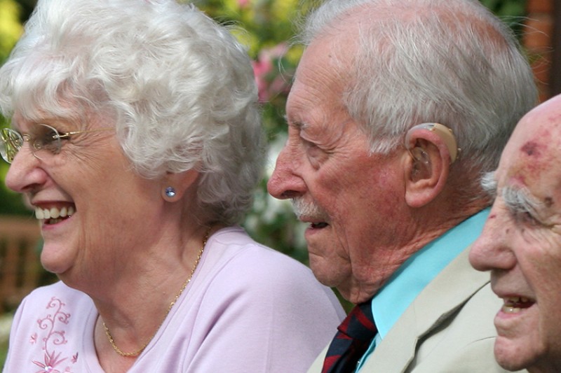 Three older people sitting in a park