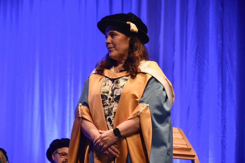 Jo Salter on stage in her ceremonial cap and gown, looking to the left