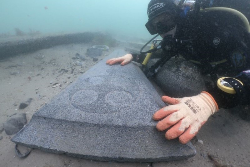 A diver holding a piece of the 'Mortar Wreck'; England's oldest surviving shipwreck in Studland Bay