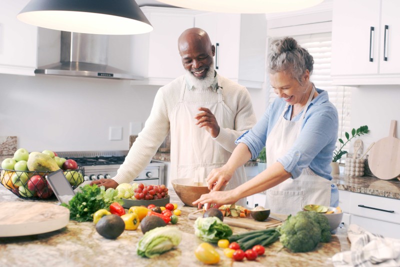 An older couple preparing fruit and vegetables in a kitchen 