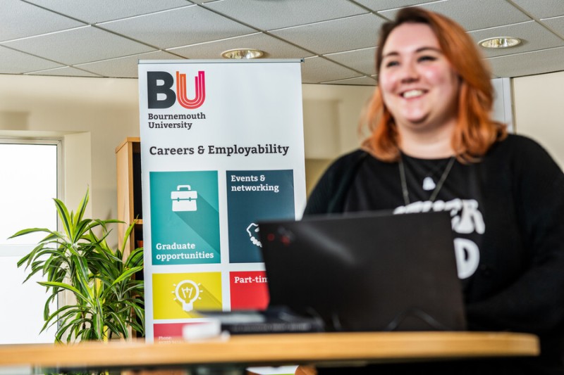 A BU student sitting in front of a Careers & Employability banner