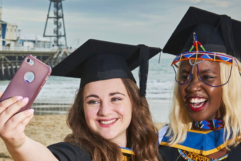 Graduates taking a selfie by the pier