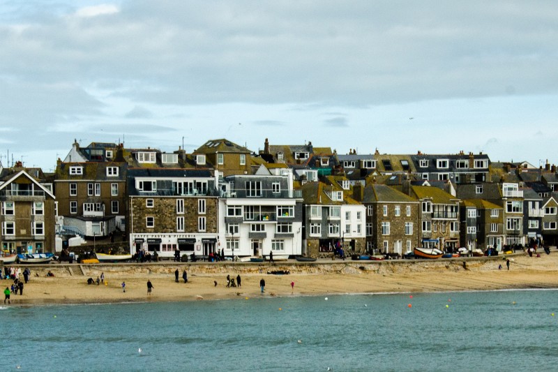 Sea in the front, a sandy beach behind and some old looking buildings in the background