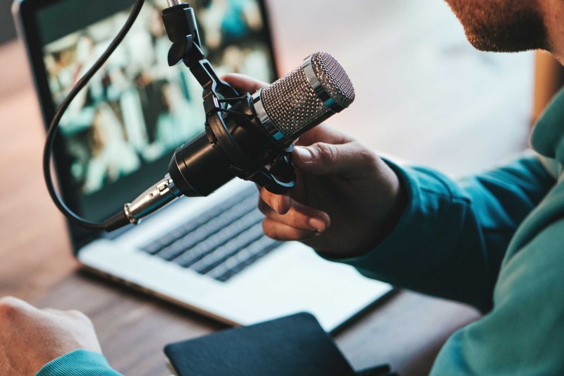 A man speaking into a microphone in front of a laptop