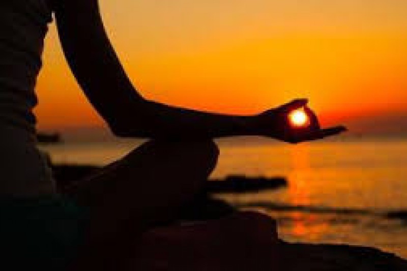 Person doing a yoga pose on a beach at sunset