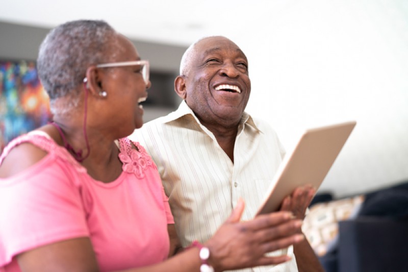 Two senior people looking at content on a tablet device and laughing