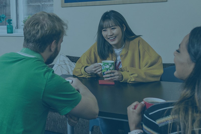 Three students talking in a halls of residence kitchen