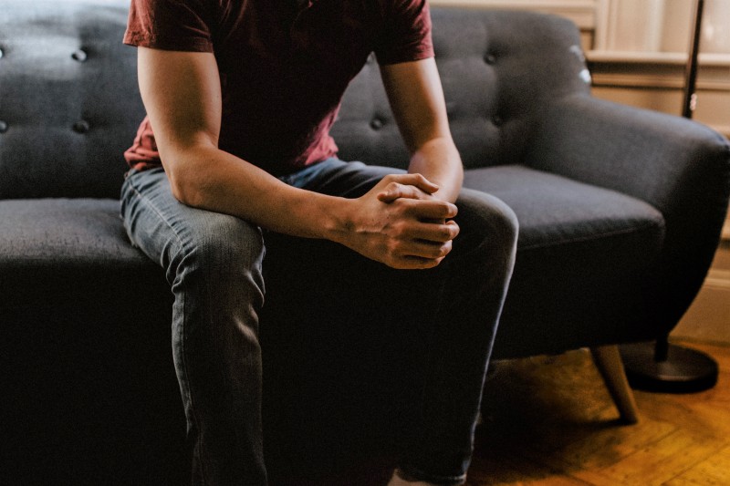 Man sat on sofa, hands together