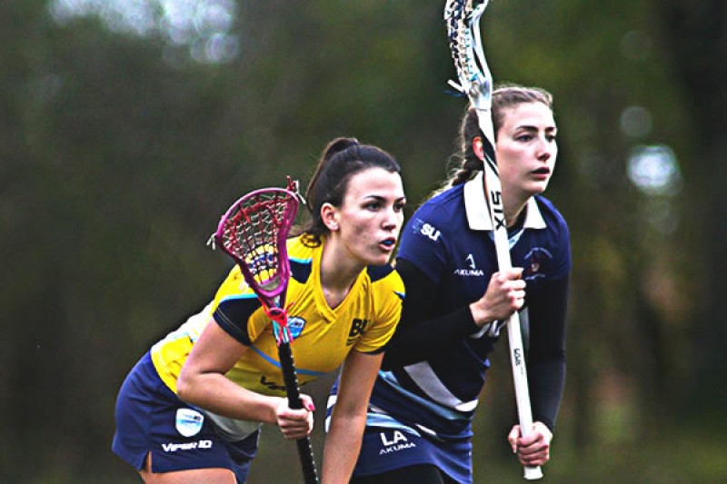 Two woman playing Lacrosse