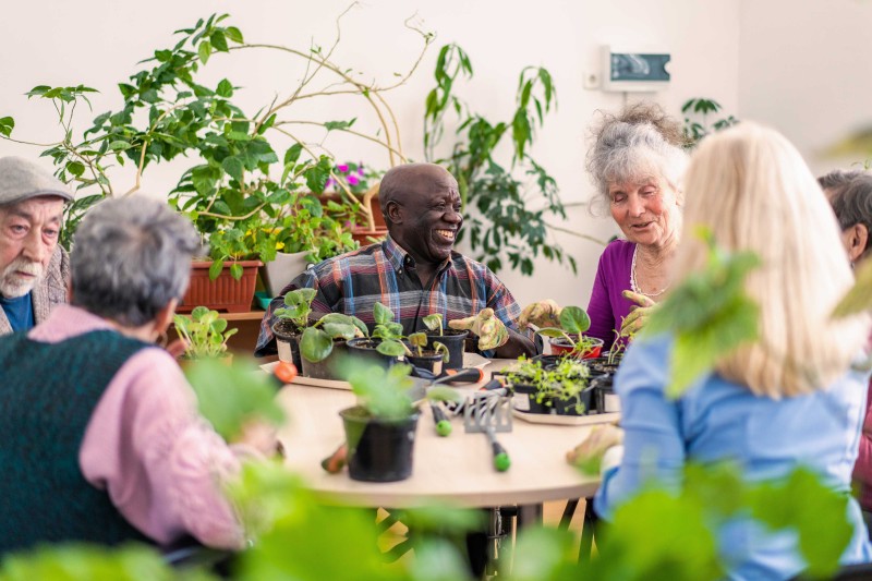 A group of older people sat around a table talking and laughing