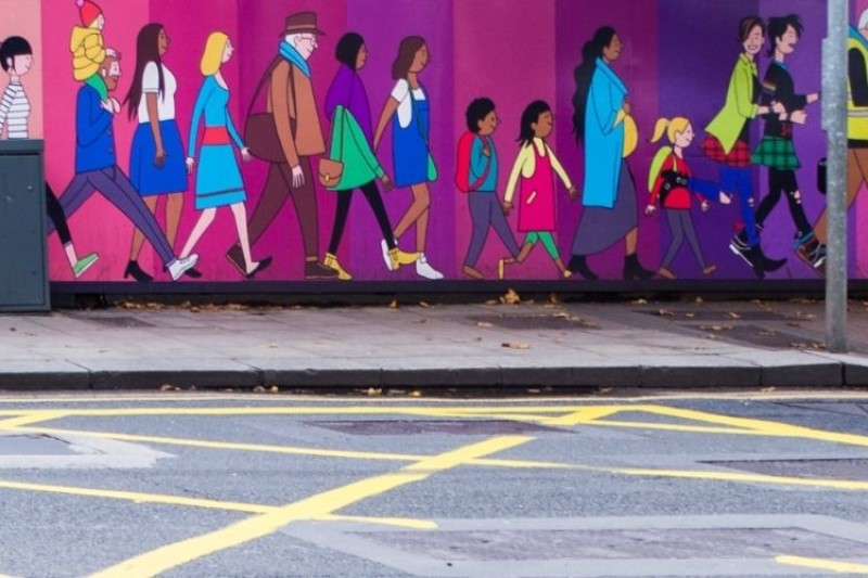 A mural of different people walking, aligning a city pavement