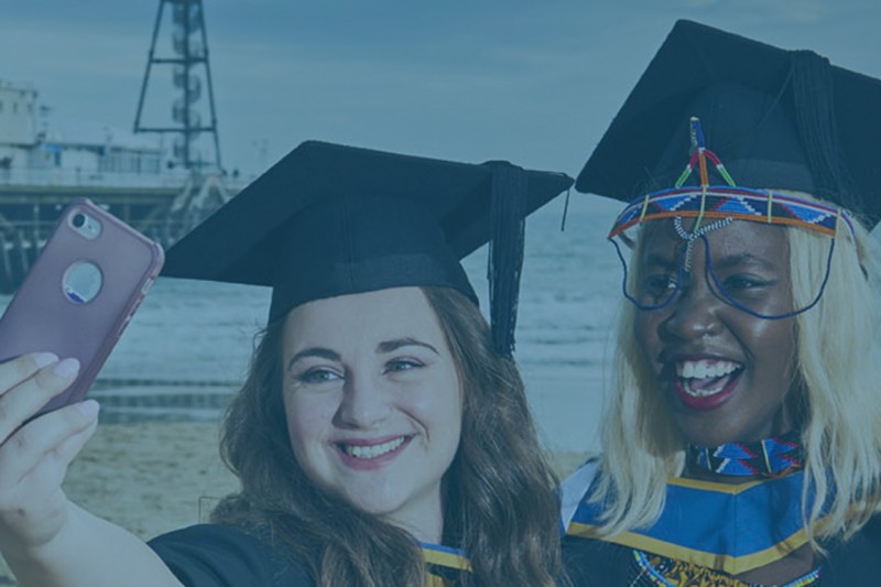 Two graduates taking a selfie on the beach