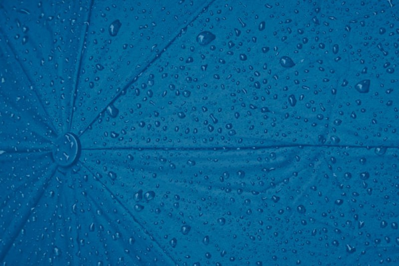 An umbrella dotted with raindrops behind a blue background