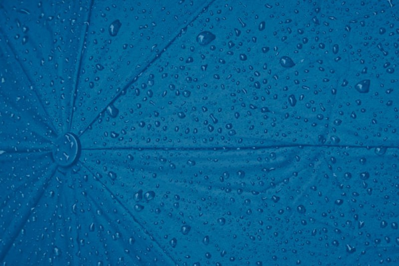 An umbrella dotted with raindrops behind a blue background