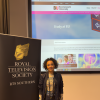 Yasmin standing next to a Royal Television Society banner with the BU website projected onto the screen behind her