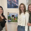 Three Marketing communication students stand amongst the art work that makes up their Earth Day exhibition