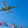 A plane flying over a range of international flags