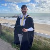 David Hicks, a Bournemouth University Lecturer in Politics, at his graduation with Bournemouth beach in the background.