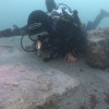 Bournmeouth University maritime archaeologist diving next to one of the two decorative gravestones on the seabed