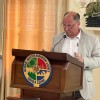 A man standing at a podium talking, on the lectern is a crest saying Sierra Leone National Disaster Management Agency