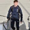 Joseph Evans walking up some steps, smiling at the camera, wearing a West Ham United tracksuit