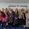 A large group of participants in the programme standing, looking straight at the camera (mostly) smiling