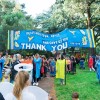 A parade of people wearing the colours of Ukraine's flag with a banner thanking people for taking them in to their homes