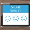 An ipad on a wooden surface with an online survey and different smiley face options 