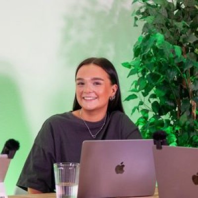 A girl smiling at the camera sat at a desk with a laptop