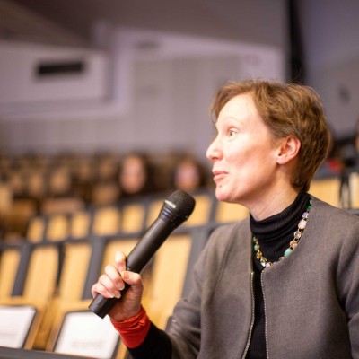 Professor Katharine Cox holding a microphone in a lecture theatre