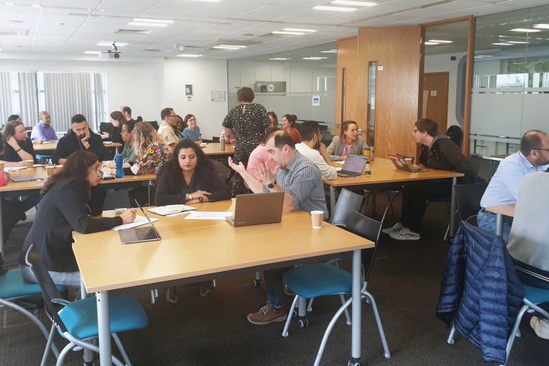 People sat around tables in a seminar room 